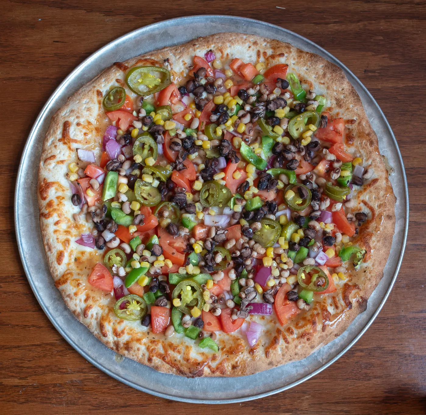 Apollo's Cowboy Caviar pizza topped with tomatoes, jalapeños, corn, black beans, and onions.