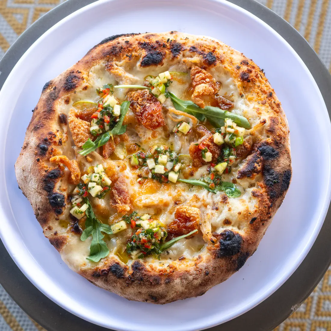 Crust's Porchetta Verde pizza with porchetta, green apple chimichurri, arugula, and crispy pork skin.